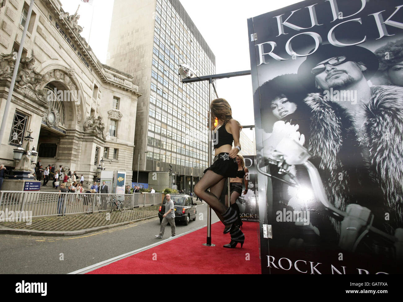Pole dancers perform on the back of a truck to advertise the new single 'All Summer Long' by American singer Kid Rock, outside Waterloo Station in central London. Stock Photo