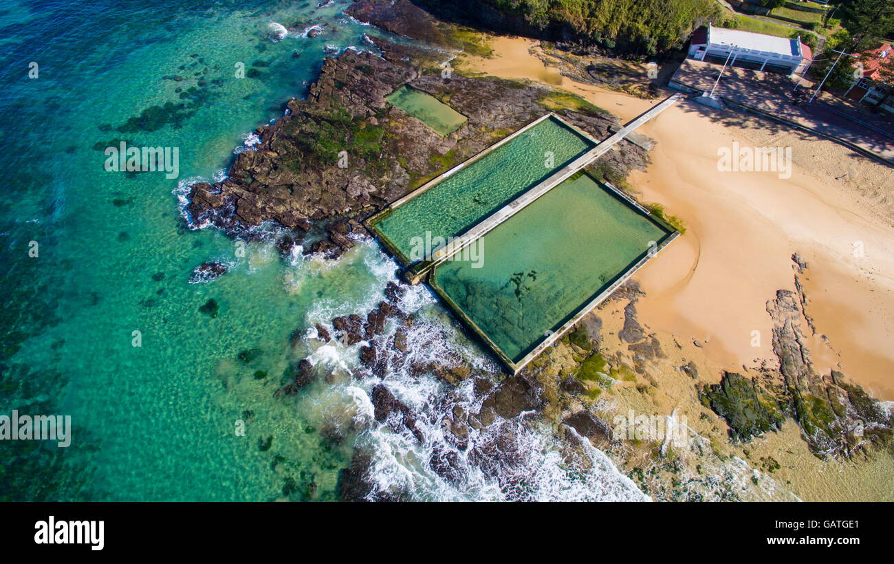 A lone swimmer swims laps in the Austinmer ocean rock pools, viewed from above. Stock Photo