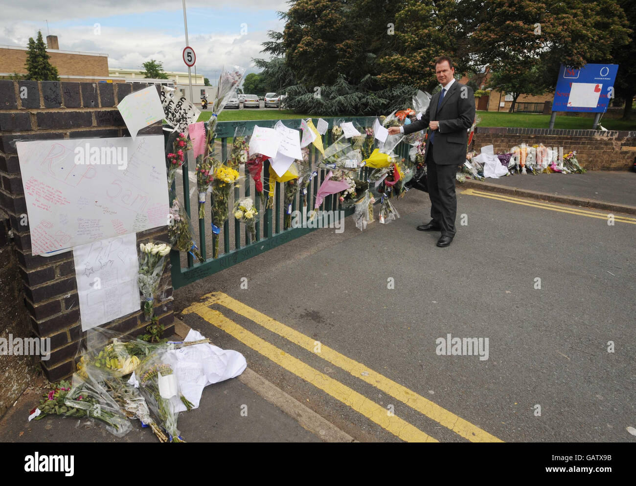 Severn Vale School Head Teacher Peter Rowland views the messages and floral tributes to Sam Leeson at his school gate in Quedgeley, Gloucester. Stock Photo