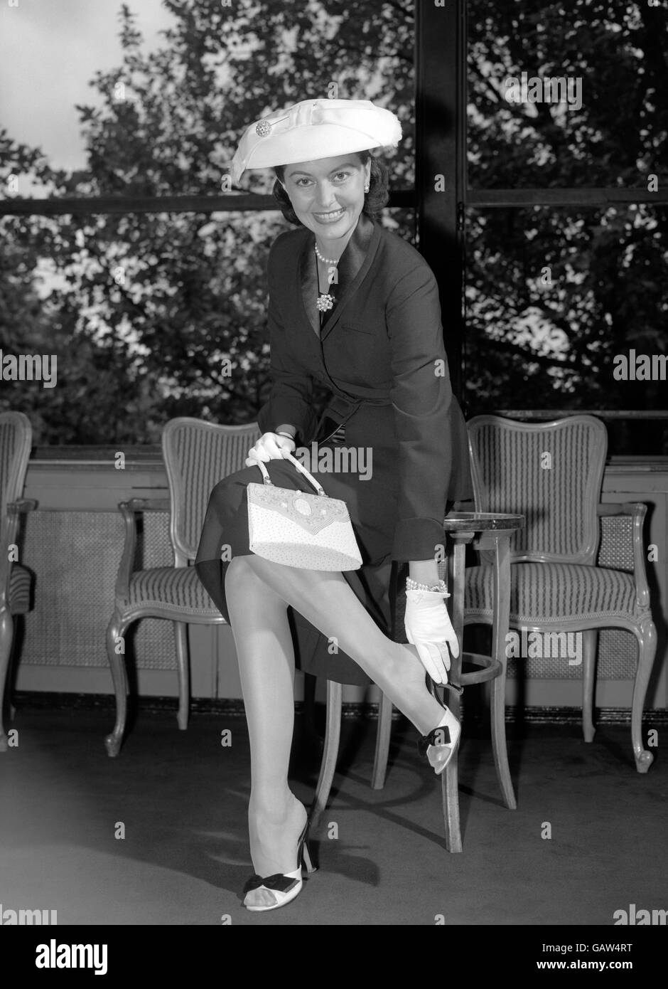 Smiling new arrival in London is Hollywood actress and dancer Cyd Charisse, pictured with a cameo-decorated handbag - at the Savoy Hotel this evening (Saturday) Stock Photo