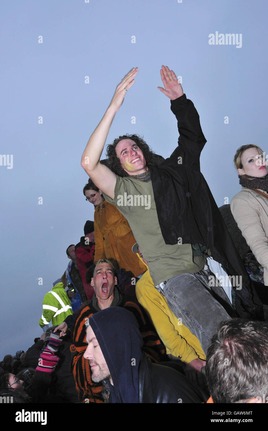 Revelers chant in the early morning drizzle as bad weather and rain prevent the sun shining on the morning of the summer solstice at Stonehenge, Wiltshire. Stock Photo