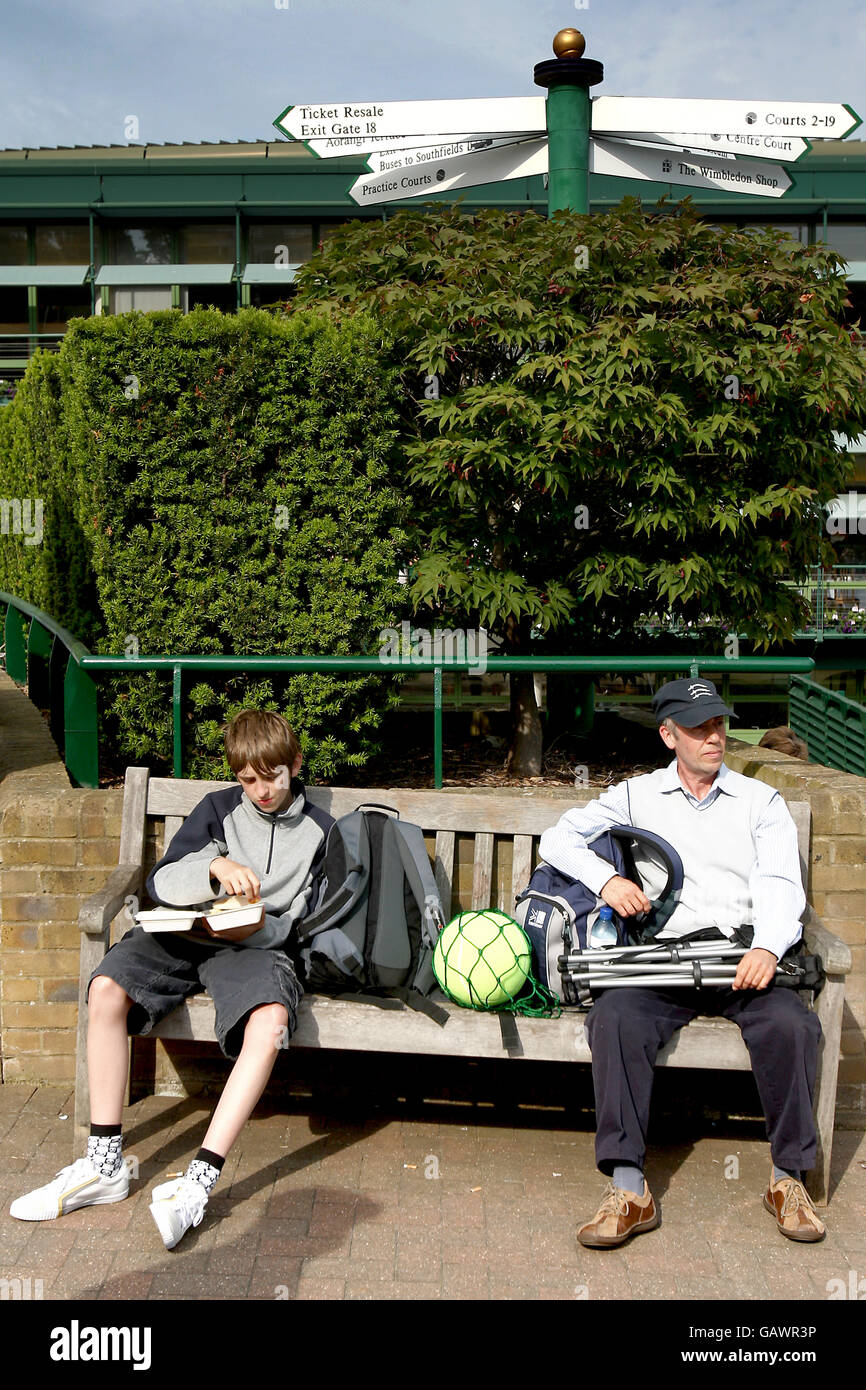 Tennis - Wimbledon Championships 2008 - Day Two - The All England Club. Two spectators take a moments rest on one of the benches at Wimbledon Stock Photo
