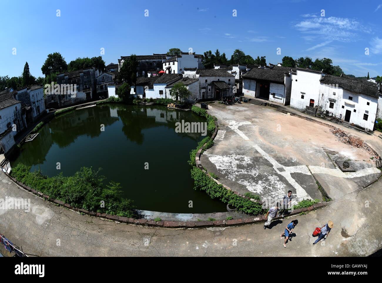 (160706) -- LANXI, July 6, 2016 (Xinhua) -- Tourists walk along the Bell Pond in Zhuge Village in Lanxi City, east China's Zhejiang Province, July 5, 2016. The Zhuge Village, which has more than 660 years of history, is home to descendents of Zhuge Liang, an important military strategist and inventor serving as the Prime Minister of the Shu Kingdom in the period of the Three Kingdoms (220-265). The village was designed and constructed by Zhuge Dashi, 27th descendant of Zhuge Liang, following the design of the Bagua (Eight Diagrams) principles of Fengshui. (Xinhua/Han Chuanhao) (lfj) Stock Photo