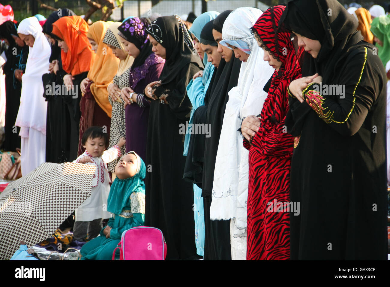 Philippines. 6th July, 2016. A young girl looks on while Muslim adults pray at the Quirino Grandstand. Filipino Muslims from nearby cities converged at the Quirino Grandstand in Manila to celebrate the end of Ramadan. Eid al-Fitr marks the end of the holy month of fasting in Islam. © J Gerard Seguia/ZUMA Wire/Alamy Live News Stock Photo