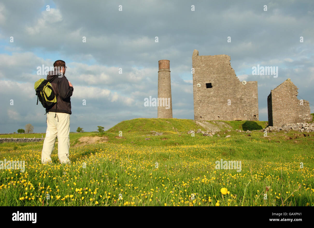 A male walker pauses to survey the remains of Magpie Mine near Sheldon, Peak District National Park Derbyshire England UK - May Stock Photo