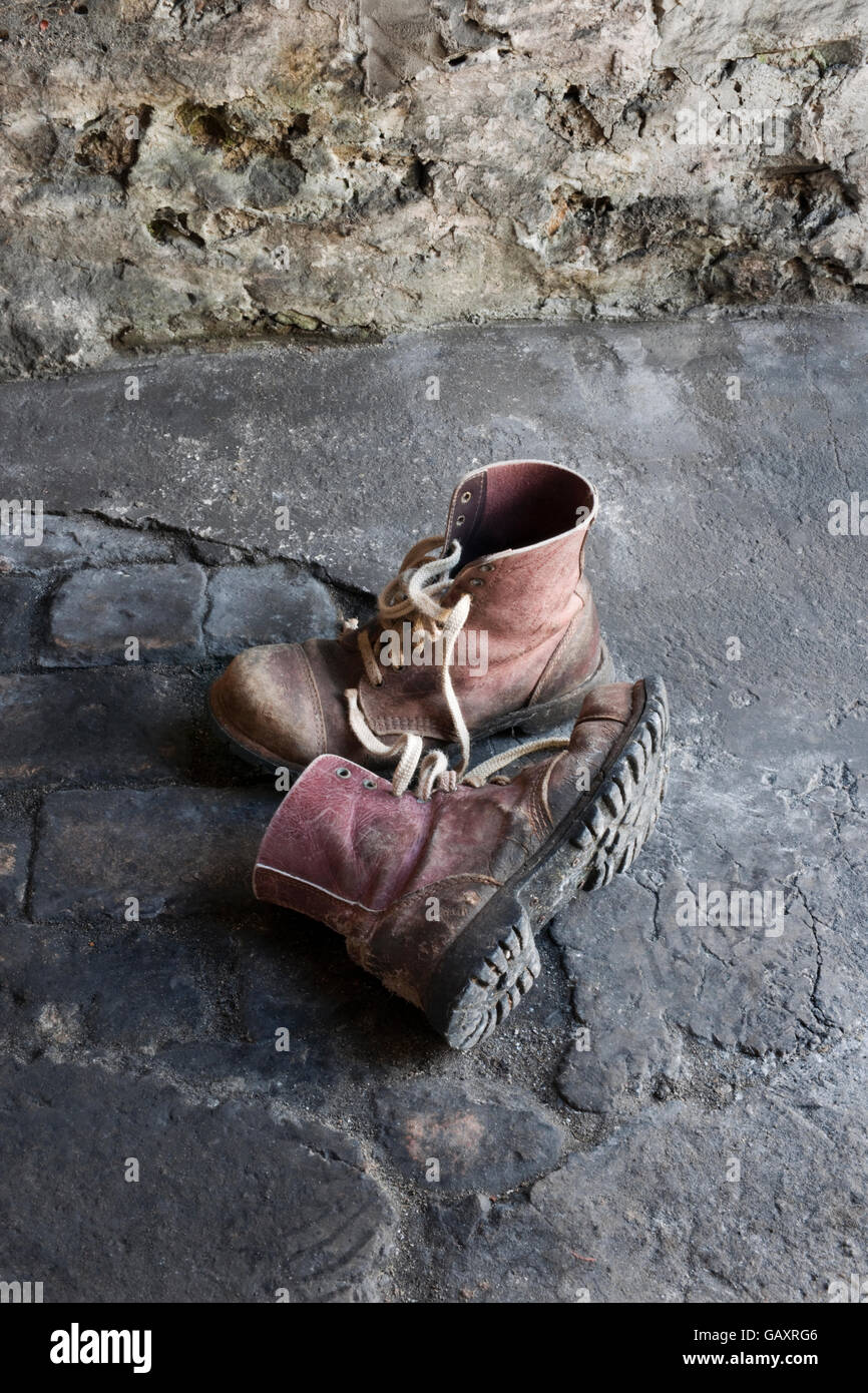 A pair of old leather work boots on workshop floor Stock Photo