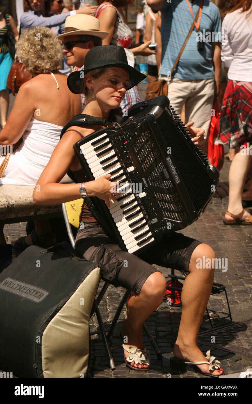 Girl Busker playing accordion in Rome, in a sunny busy tourist filled