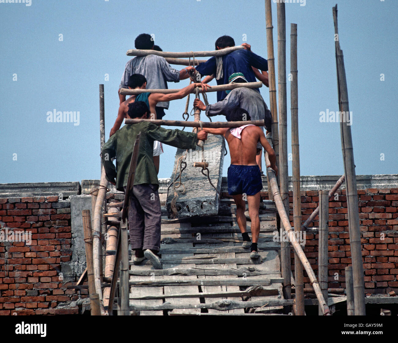 Building labourers manually lifting heavy concrete slabs, Chengdu, Sichuan Province, China Stock Photo