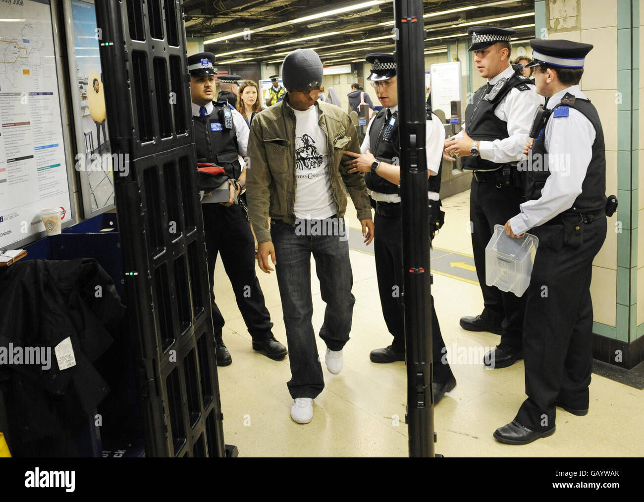 PASSENGER FACE HAS BEEN PIXELATED BY PA PICTURE DESK ON ADVICE FROM METROPOLITAN POLICE Police officers search commuters for knives with the aid of a metal detector as they pass through Mile End tube station in London. Stock Photo