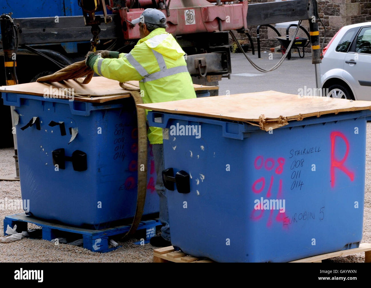 Workers remove containers of rubble taken from the cellars at Haut de la Garenne, Jersey. Stock Photo