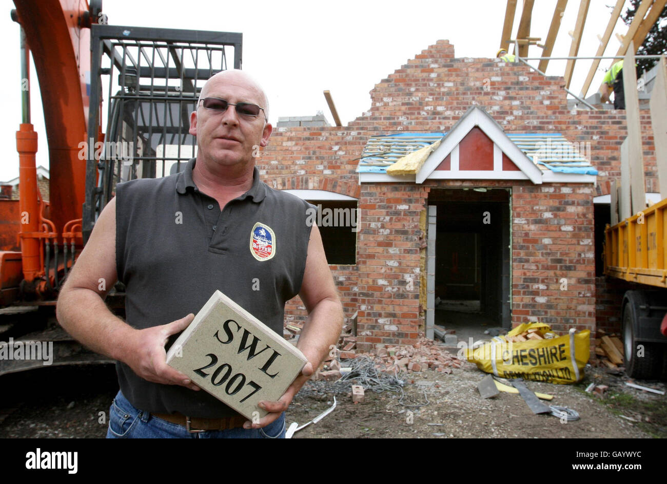 Stephen Woodfinden-Lewis holds the date stone from his house as demolition workers knock down the 600,000 new build in Woodford, Cheshire, after council planners ruled it was two feet too tall. Stock Photo