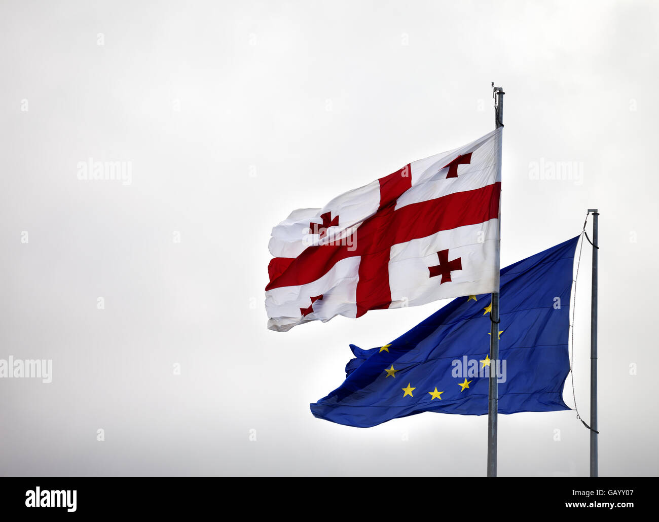 Flags Of Georgia And European Union In Cloudy Sky At Gray Day Stock flags-of-georgia-and-european-union-in-cloudy-sky-at-gray-day-stock
