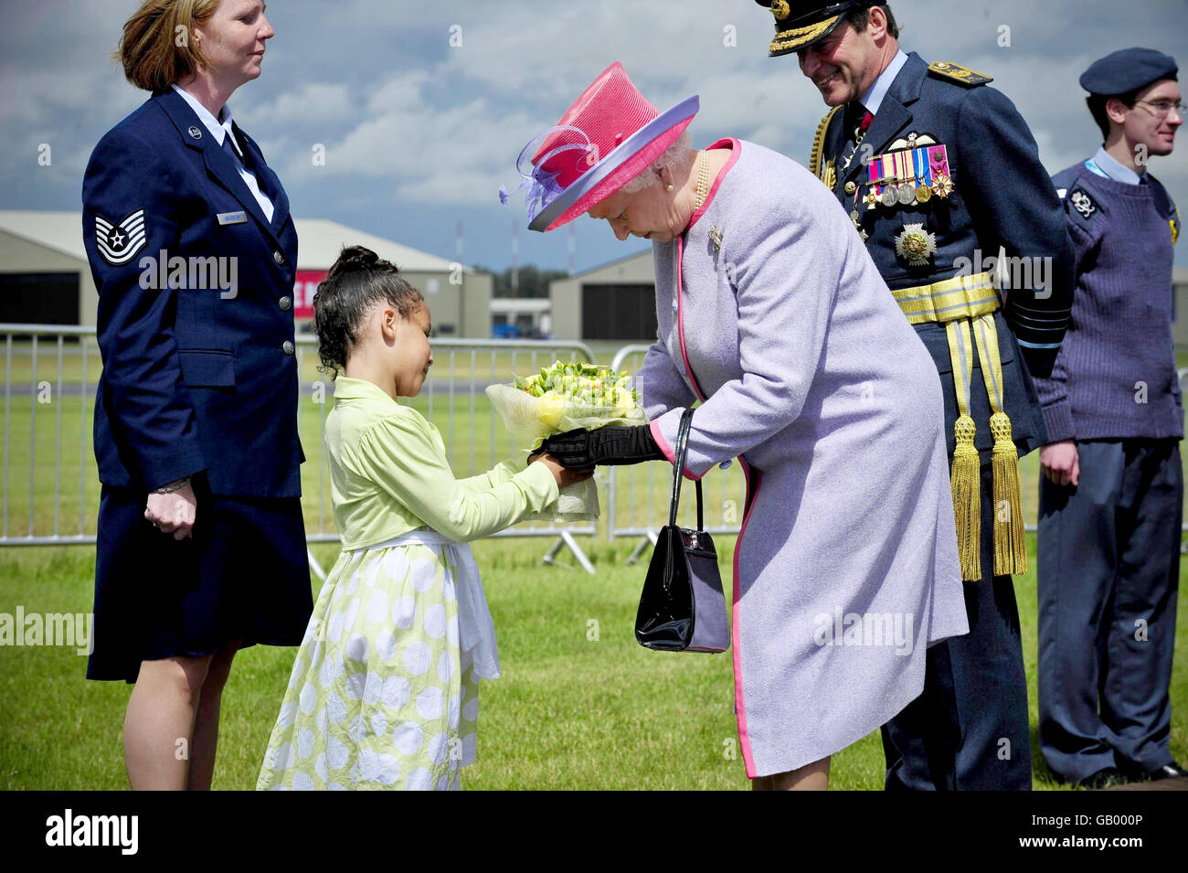 Britain's Queen Elizabeth II accepts flowers from Soleece Anabwani, 6, at RAF Fairford, after presenting new Queen's Colours jointly to the RAF in the United Kingdom and the Royal Air Force Regiment, at the opening of the Royal International Air Tattoo. Stock Photo