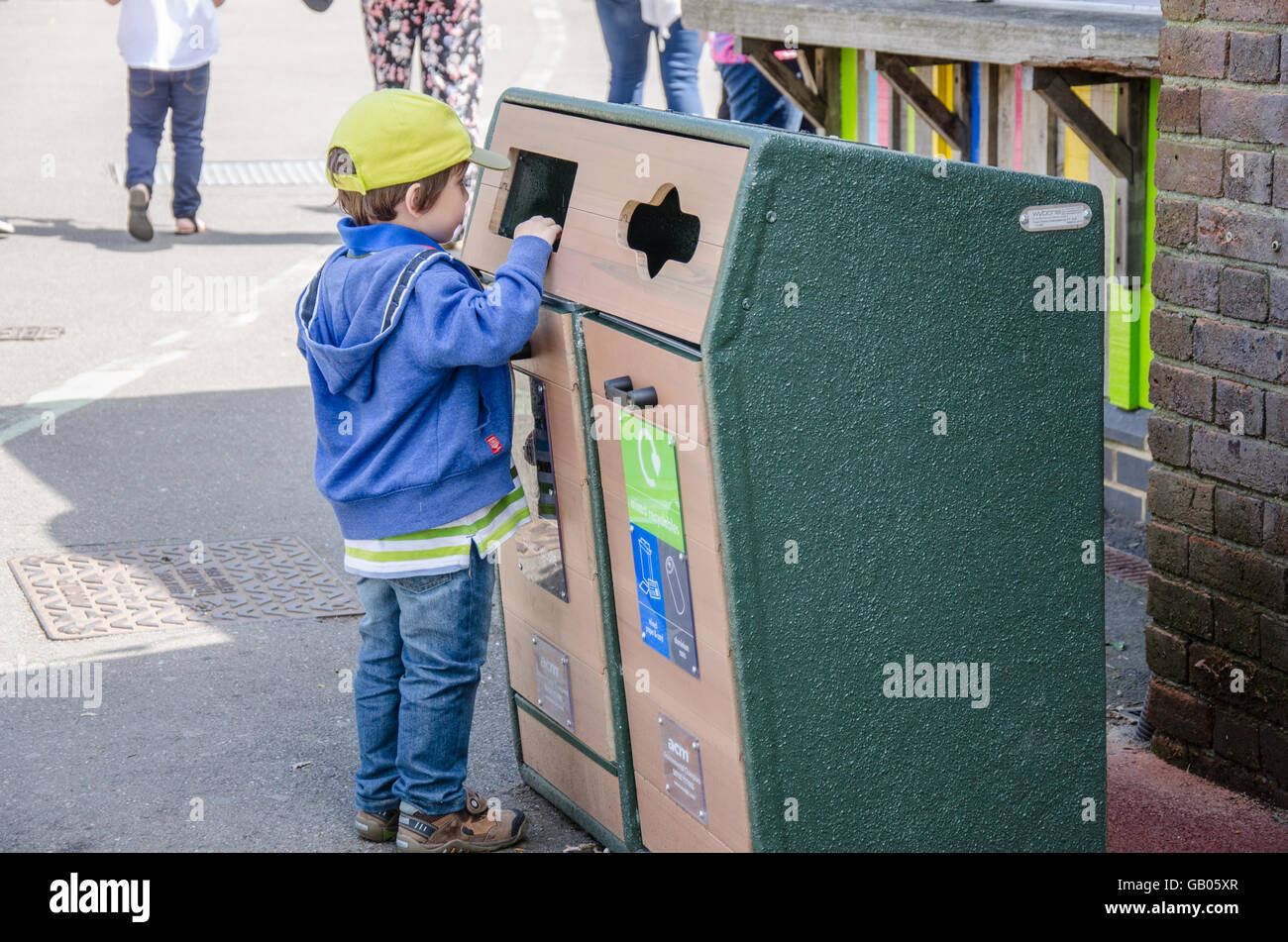 A small boy throws some rubbish in a rubbish bin. Stock Photo