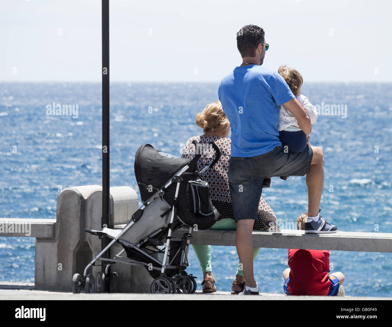 Young family looking out to sea. Stock Photo