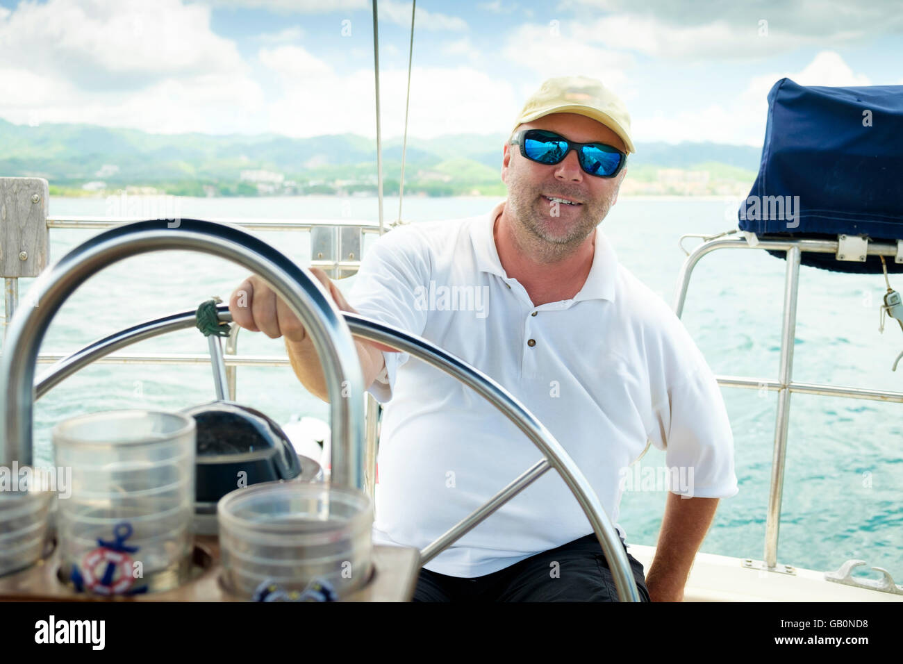 Sail boat captain behind the steering wheel of his vessel. Sailboat