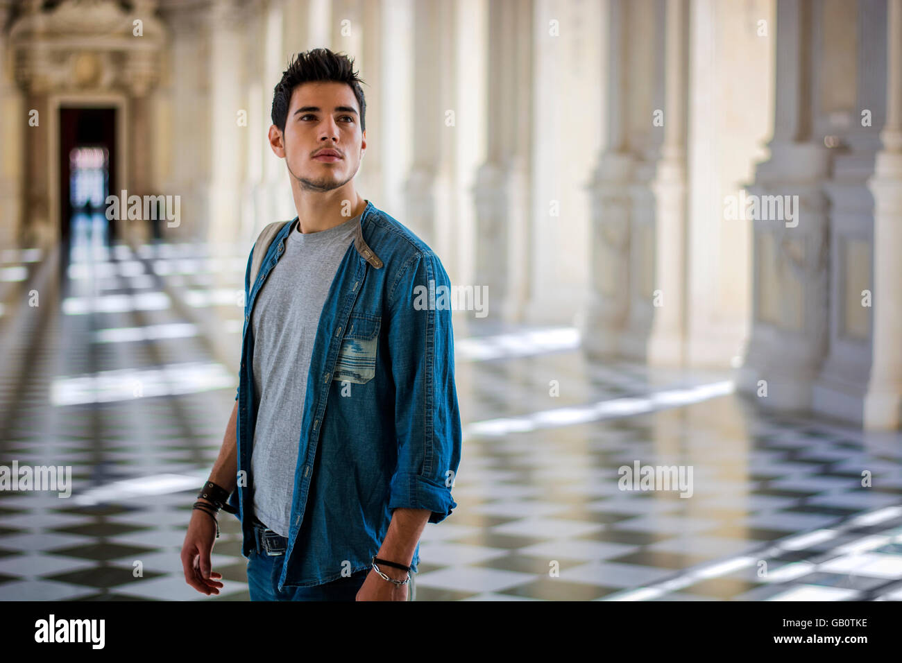 Half Body Shot of a Thoughtful Handsome Young Man, Looking Away Inside a Museum Stock Photo