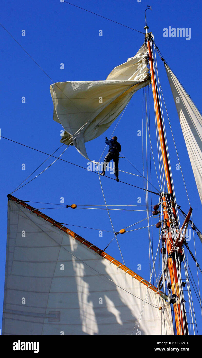 A crewmember aboard the Mariette sets a topsail high above the deck as