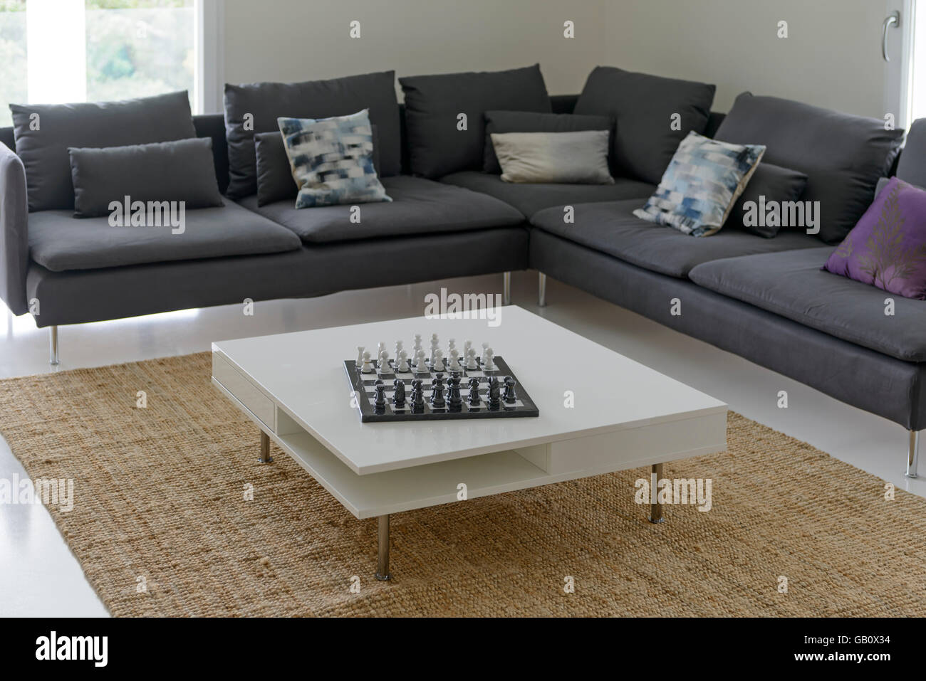Living room with a big L shaped sofa and a chess board on the center table Stock Photo