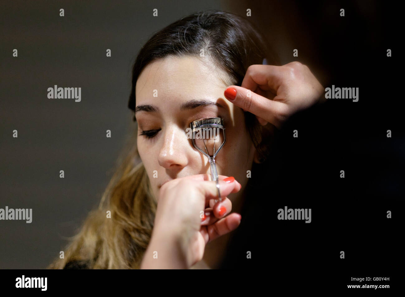 Professional make up artist using eyelash curler on client Stock Photo