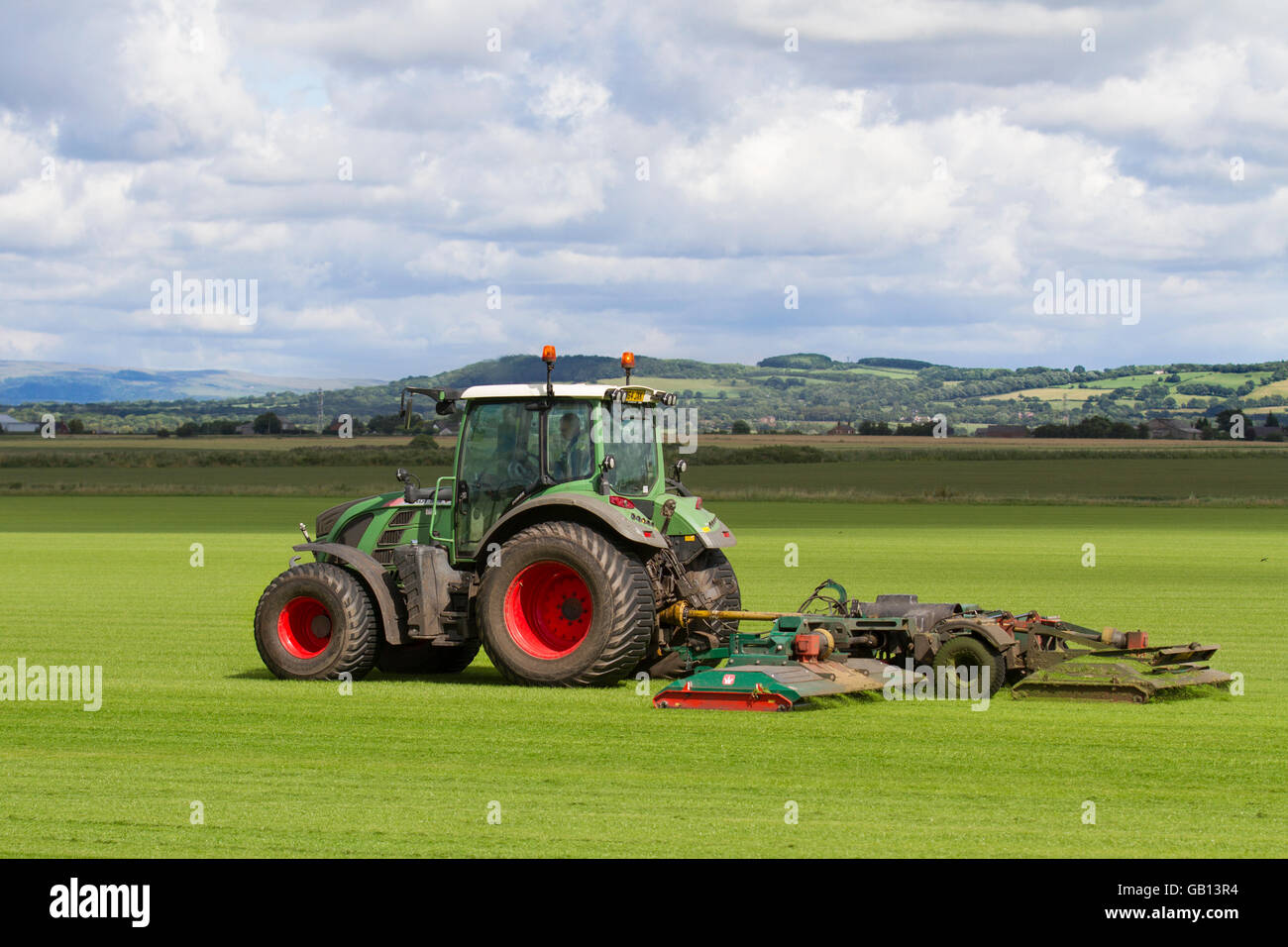 A farmer mowing field of commercial turf in Burscough, Lancashire, UK,  driving a Fendt 514 Vario tractor mowing a new crop of grasses, green,  grass, nature, lawn, grow, plant, growth, field, background,