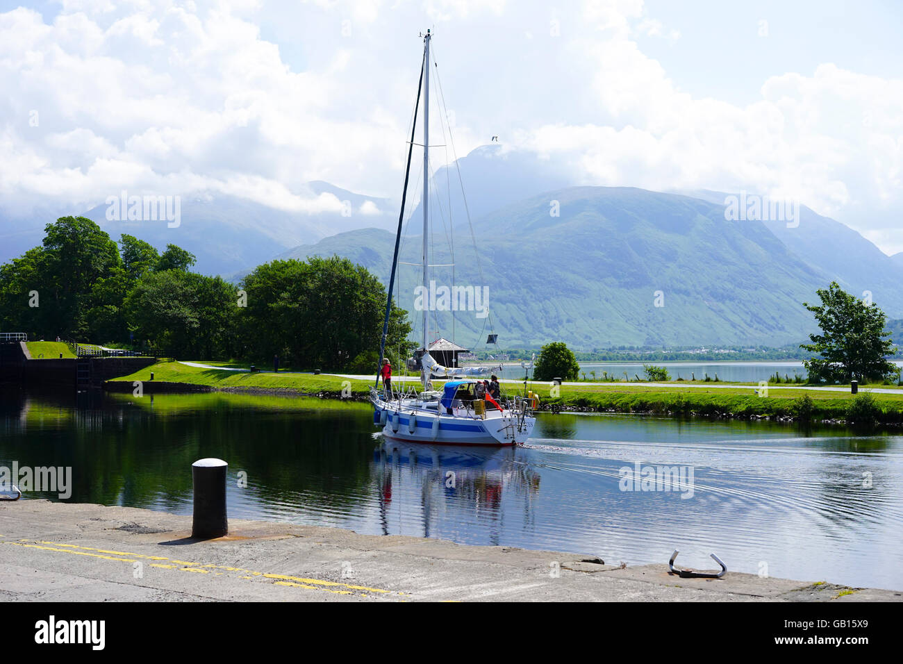 Sailing boat entering the first Lock on the Caledonian Canal at Corpach with Ben Nevis in low cloud,Corpach, Scotland,UK. Stock Photo