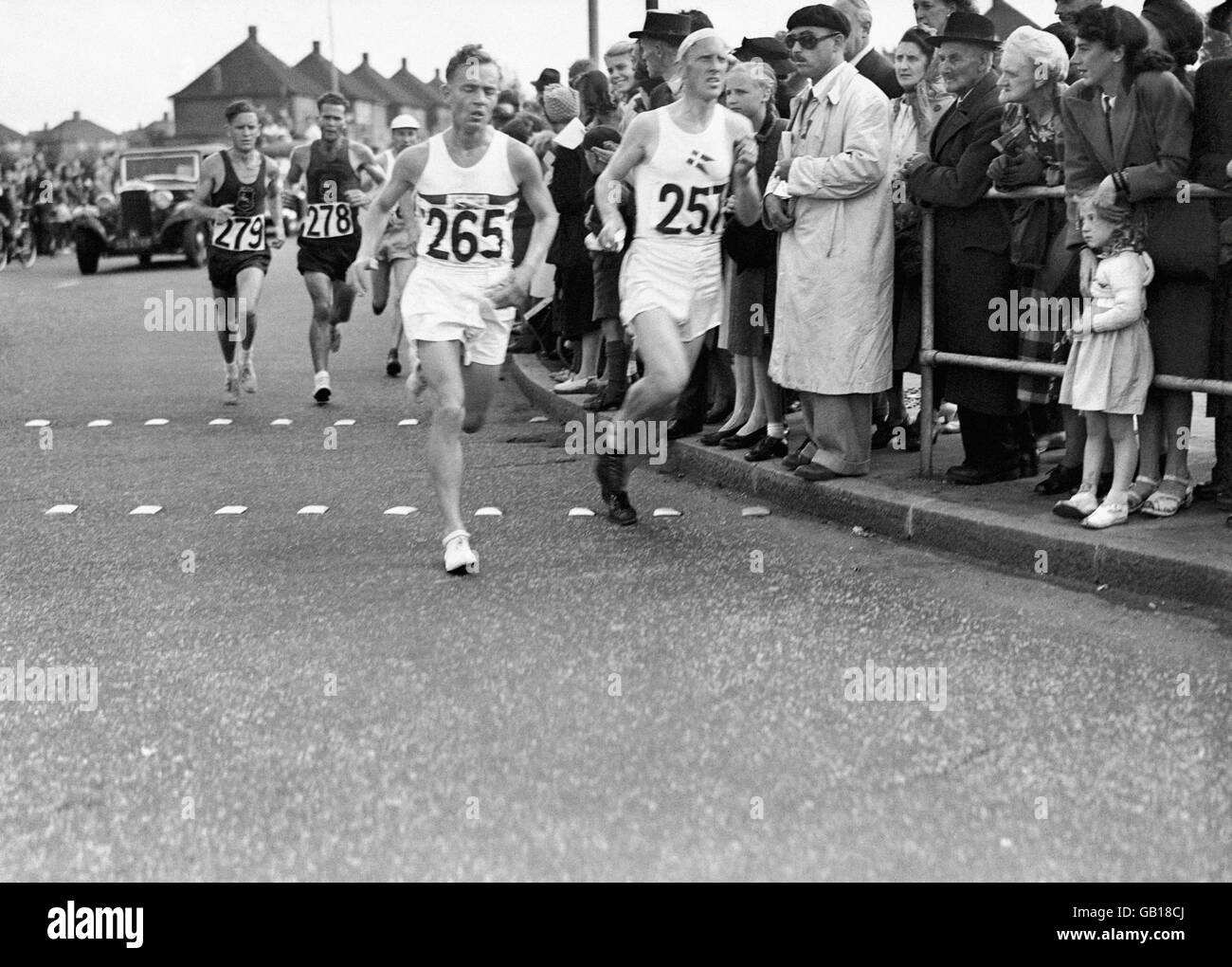 Stanley Jones of Great Britain leads some of the runners through Kingsbury in the Marathon. Next to him is Henning Larsen of Denmark and behind them (279) is Sydney 'Syd' Luyt of South Africa. Stock Photo