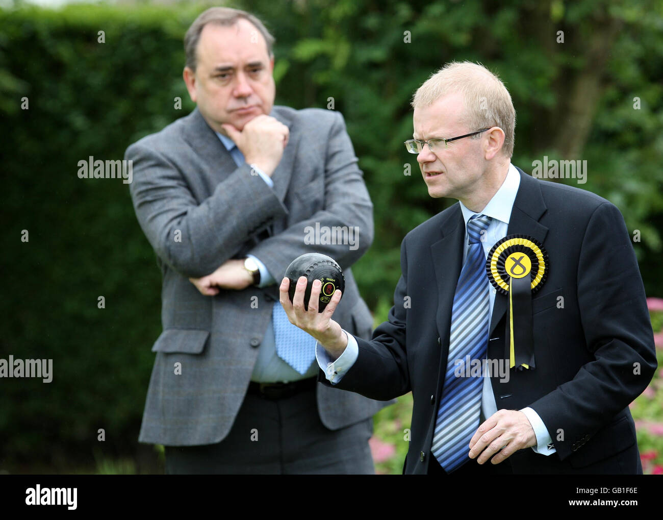 First Minister Alex Salmond with SNP candidate for Glasgow East, John Mason (right) who plays a shot during a game of bowls while visiting Garrowhill Bowling Club, to highlight support for pensioners in the citys east end. Stock Photo