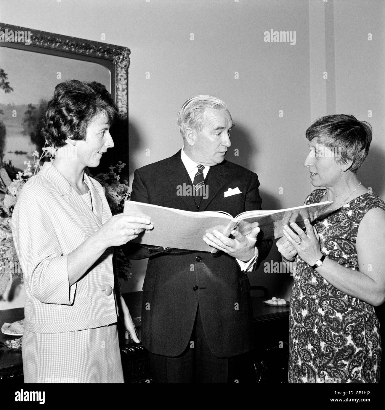 Australian Deputy High Commissioner John Knott (c) chats to the captains of the two teams, Australia's Heather McKay (l) and England's Janet Shardlow (r), as they peruse one of the albums of photographs from the Ashes series which were presented to the players of both teams Stock Photo