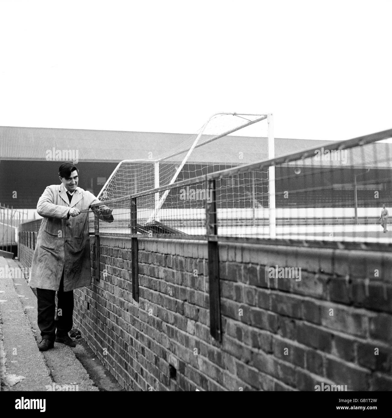 A workman tightens a bolt on the new wire mesh fencing being erected at The Den, Millwall's home ground, to prevent excited fans climbing over the wall onto the pitch Stock Photo