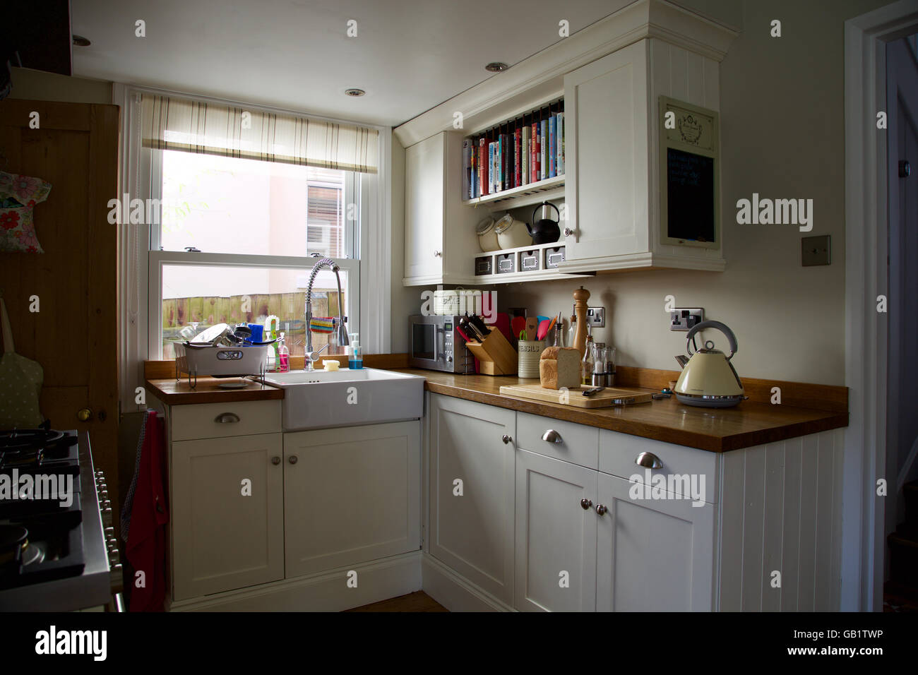 Victorian kitchen corner with window in real family home kettle loaf bread board sink cream cupboards worktop breakfast toast Stock Photo