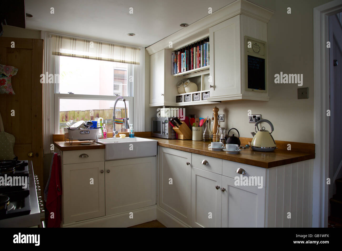 Victorian kitchen corner with window in real family home kettle tea cup pot sink cream cupboards worktop breakfast brew morning Stock Photo