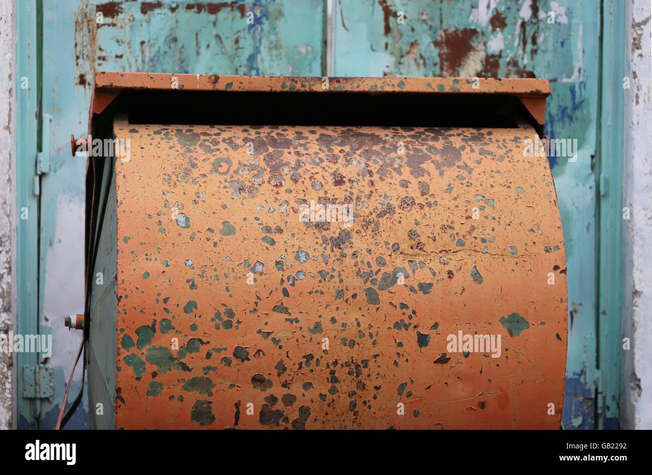 Paper Recycling Container. Rusty orange public paper recycling container, in front of old   turquoise door. Stock Photo