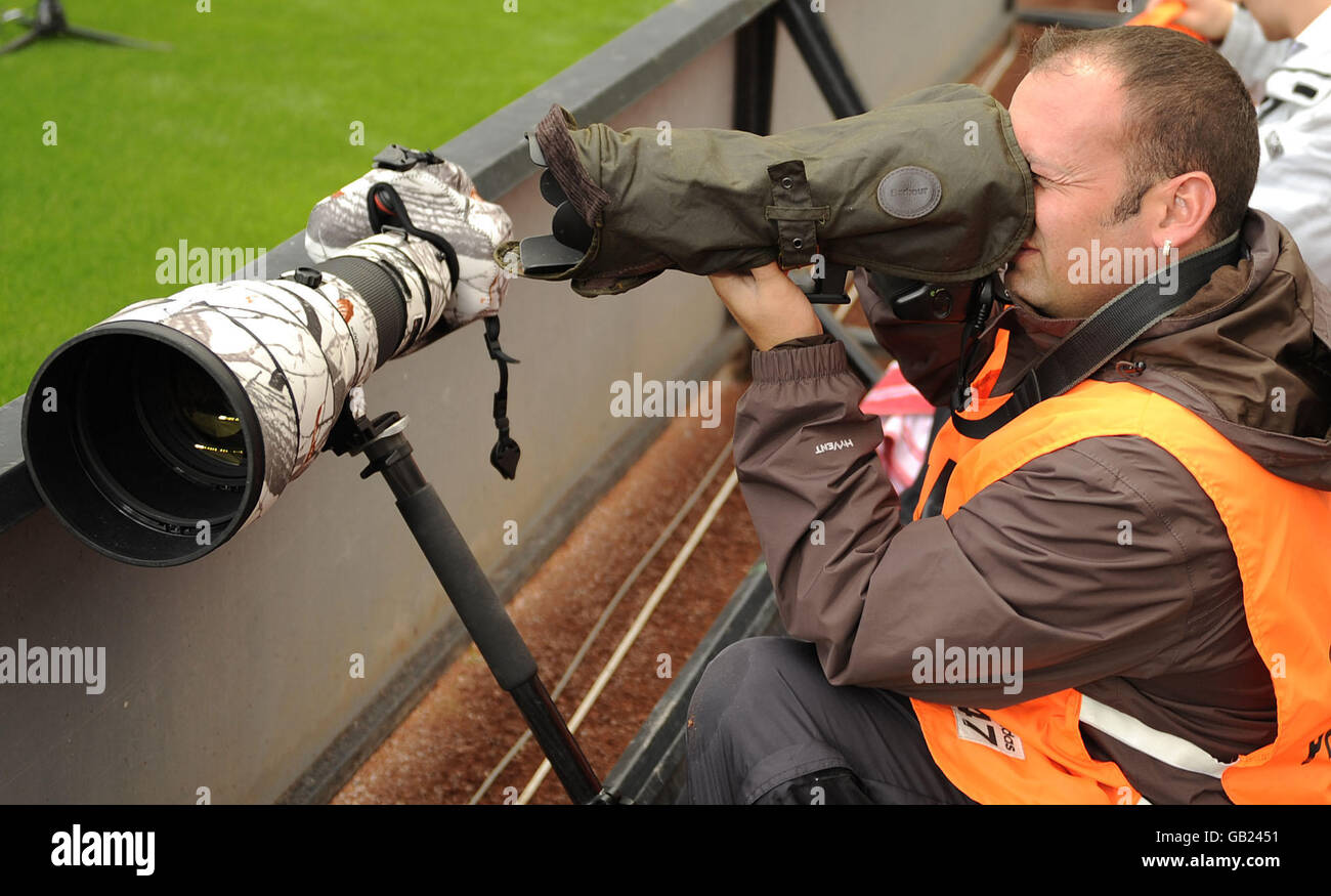 Owen Humphreys uses a dog coat to protect his camera from the rain while working at Newcastle United's ground. Stock Photo