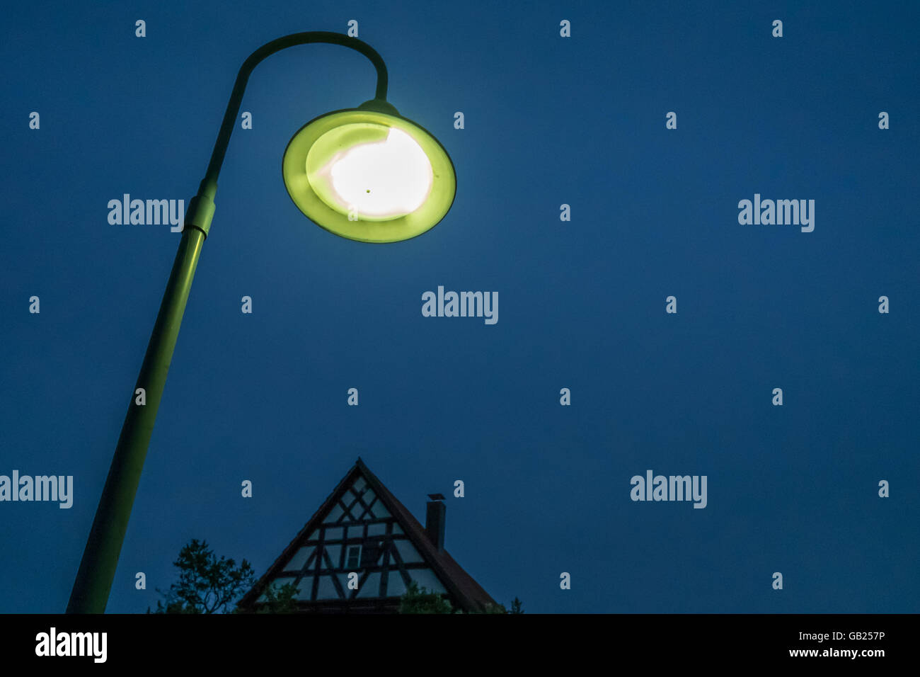 Electrical street light with half timbered house in the night Stock