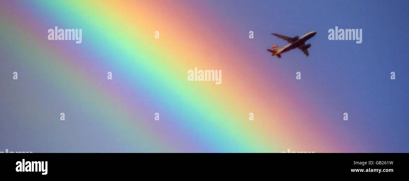 A British Airways plane flies over a rainbow as it heads towards Heathrow in London during changeable weather conditions. Stock Photo