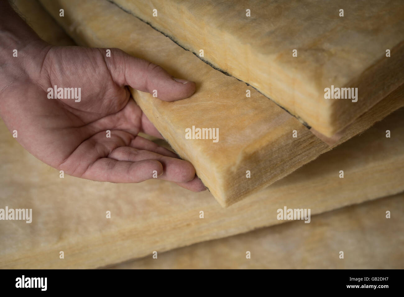 Hand holding a fiberglass batt. Image of home insulation. Stock Photo