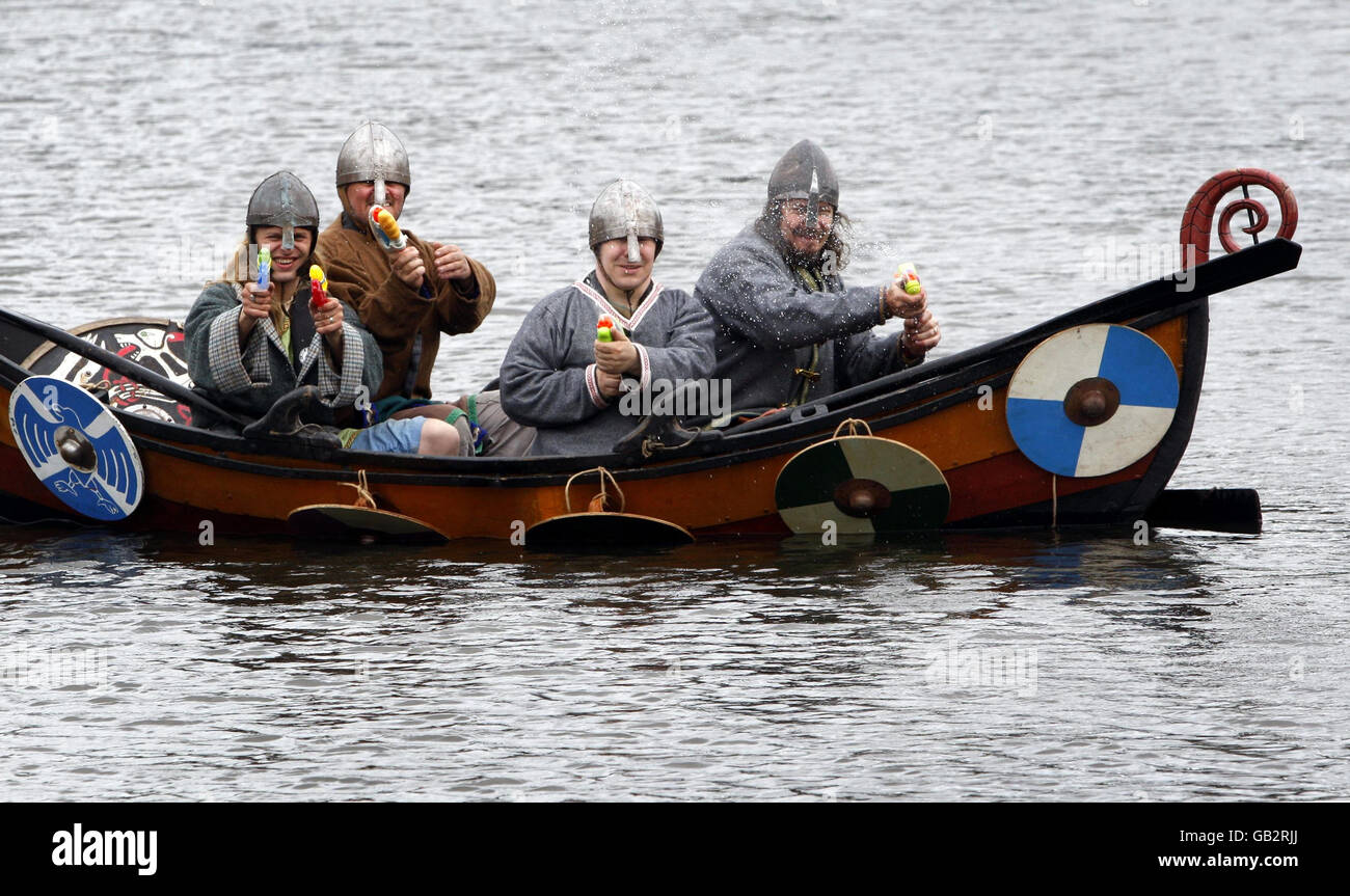 Enthusiasts at the National Living History Festival at Lanark Loch in Scotland re-enact a scene from history as Viking raiders in a longship arrive on the shores of Scotland - for a cheeky twist the Vikings are armed with water pistols instead of axes and swords. Stock Photo