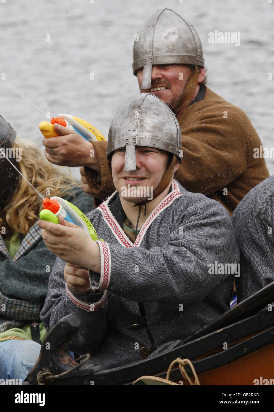Enthusiasts at the National Living History Festival at Lanark Loch in Scotland re-enact a scene from history as Viking raiders in a longship arrive on the shores of Scotland - the Vikings are armed with water pistols. Stock Photo