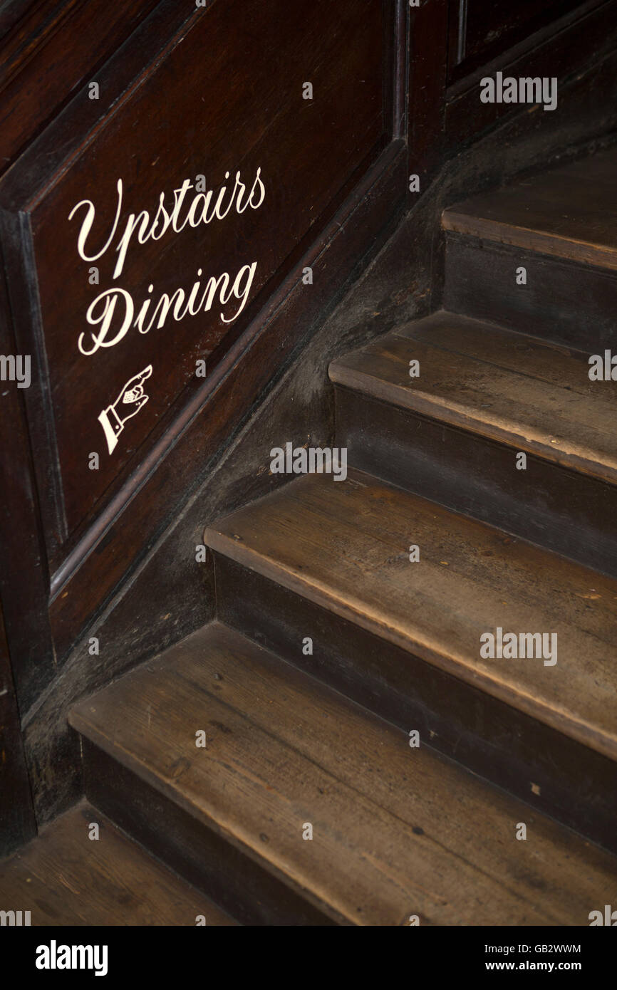 Staircase in East London, England. A sign points to  upstairs dining. Stock Photo