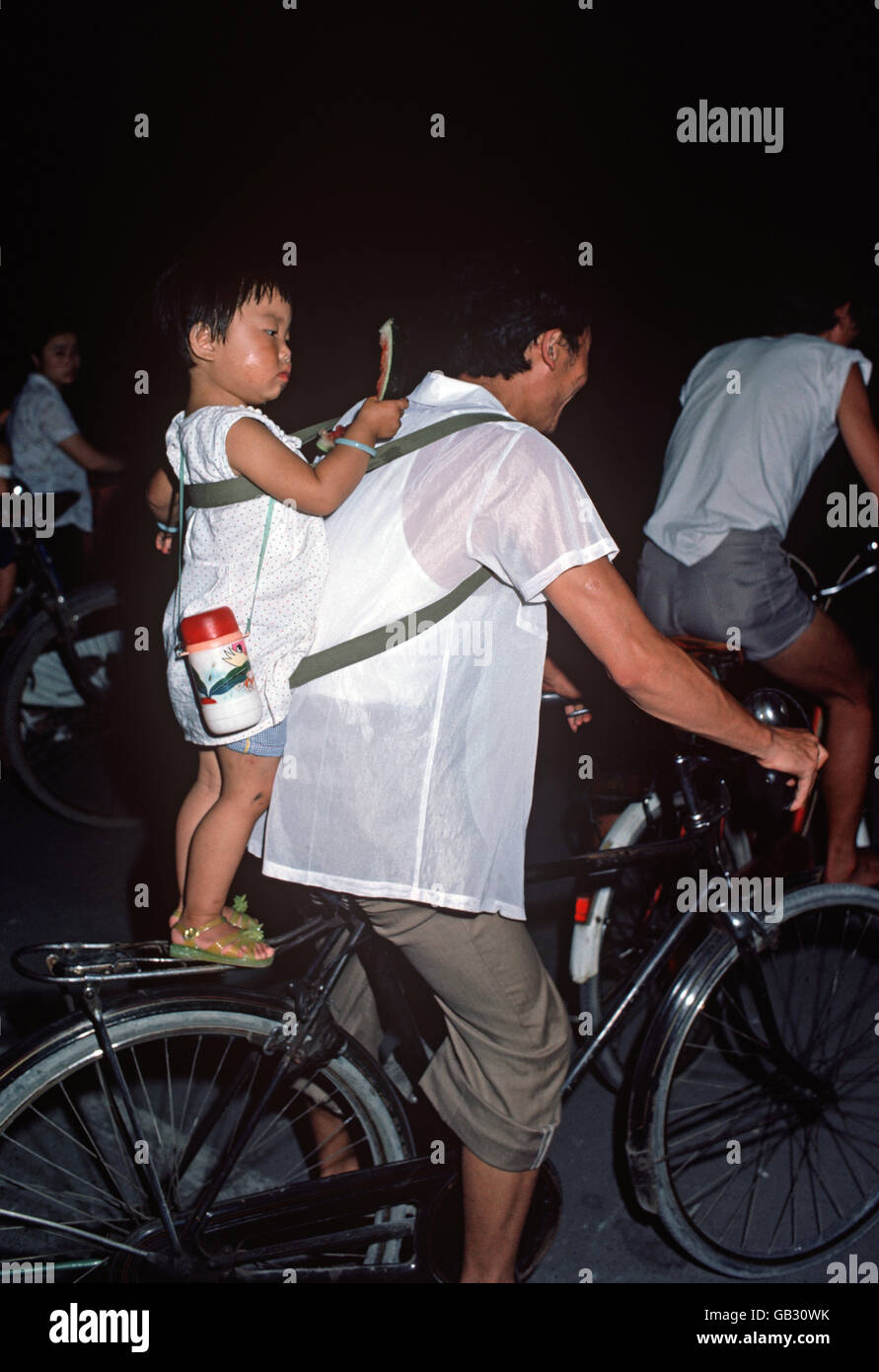 child standing on bicycle carrier, Chengdu, Sichuan, China Stock Photo