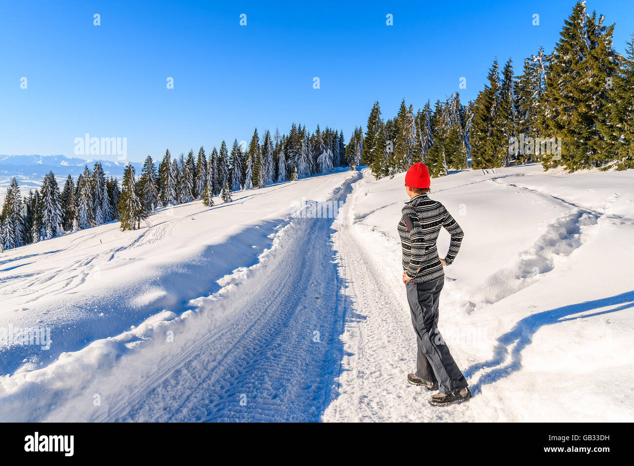 Young woman tourist standing on winter road in Gorce Mountains, Poland Stock Photo