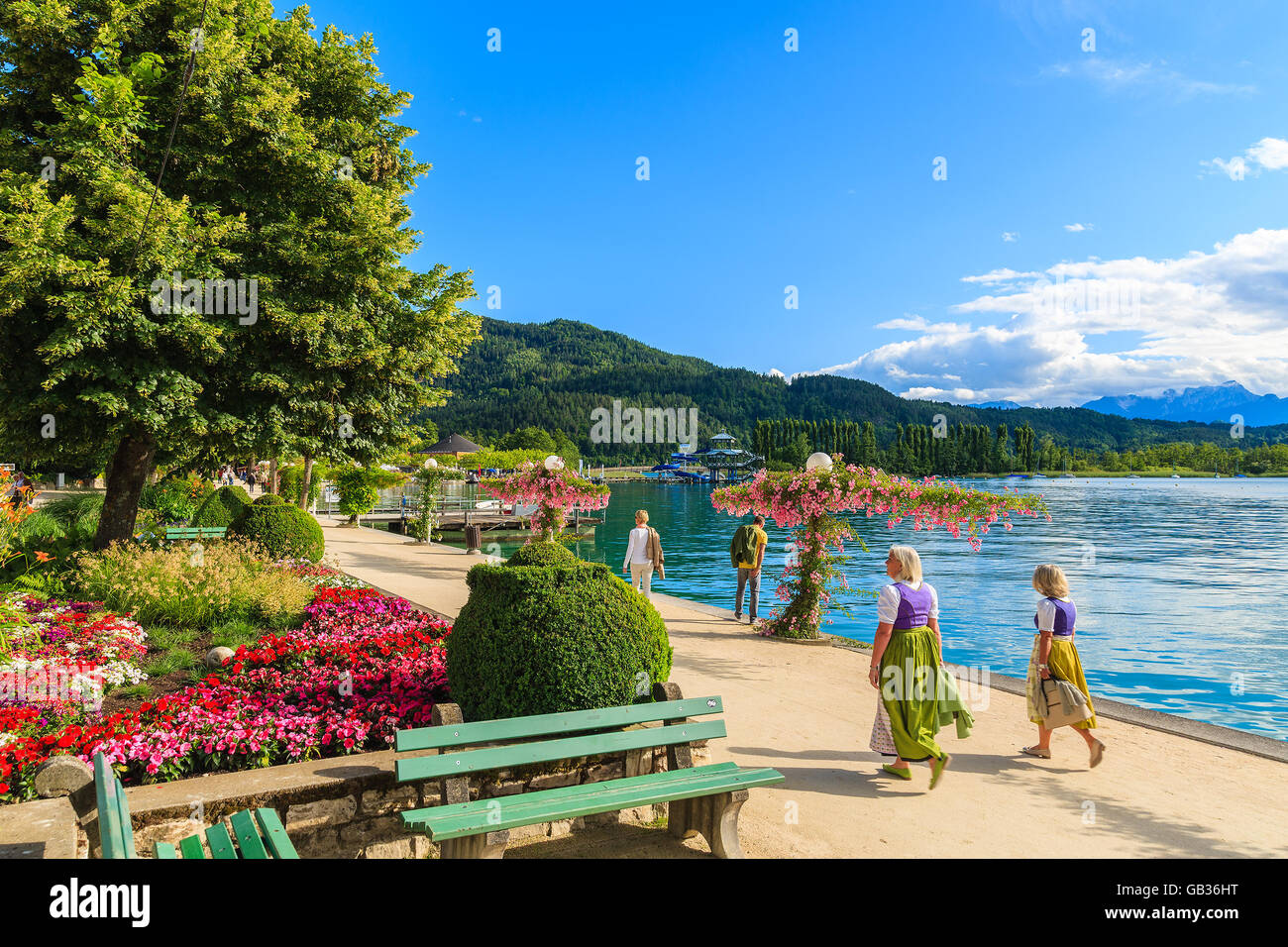 WORTHERSEE LAKE, AUSTRIA - JUN 20, 2015: two women wearing traditional clothes walking along Worthersee lake shore during summer Stock Photo