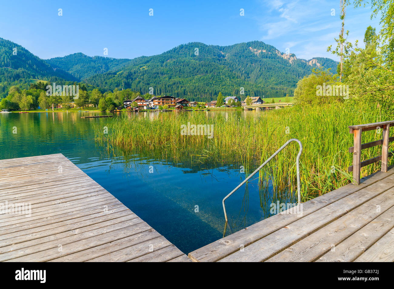 Wooden pier on shore of Weissensee alpine lake in summer landscape, Austria Stock Photo
