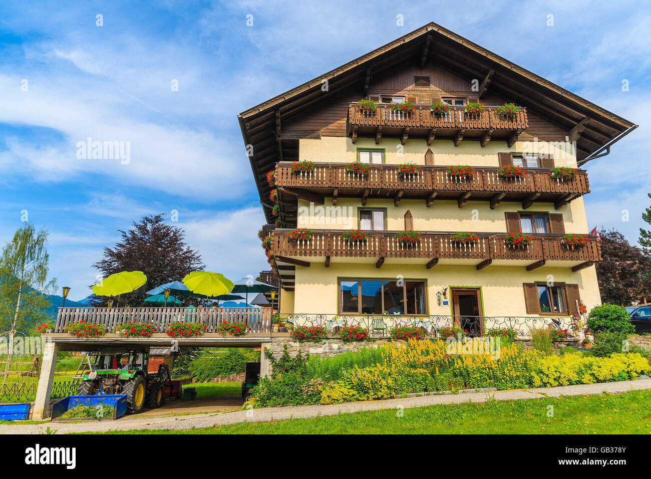 WEISSENSEE LAKE, AUSTRIA - JUL 6, 2015: Typical alpine guest house on green meadow in summer landscape of Weissensee lake, Austr Stock Photo
