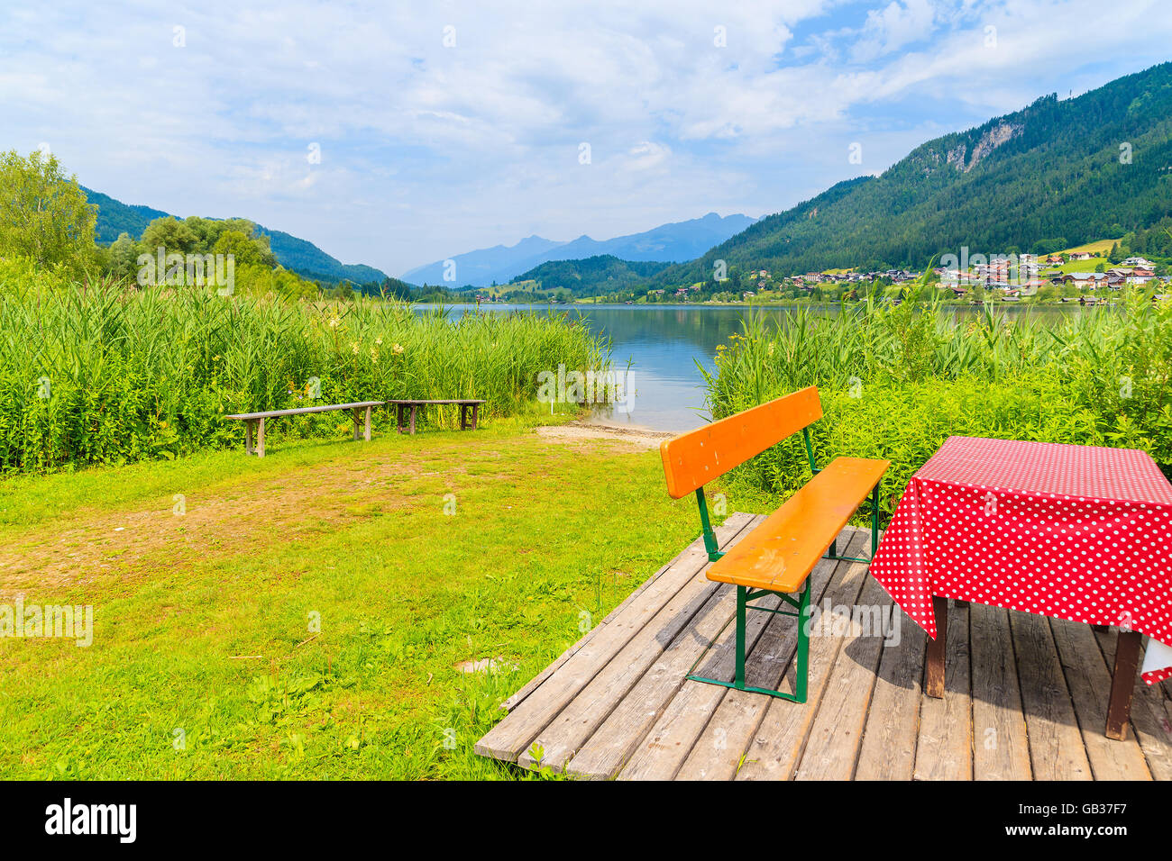 Bench with table on beach at Weissensee lake in summer landscape of Alps Mountains, Austria Stock Photo