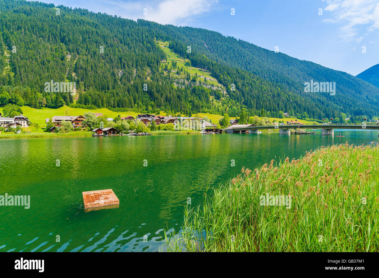 Wooden platform for swimming on green water Weissensee lake in summer landscape of Alps mountains, Austria Stock Photo