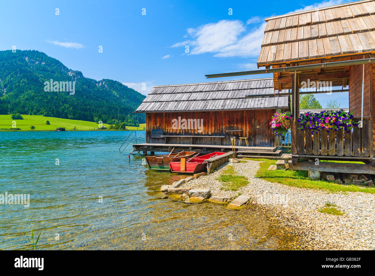 Fishing boats and wooden houses on shore of Weissensee lake in summer landscape of Carinthia land, Austria Stock Photo