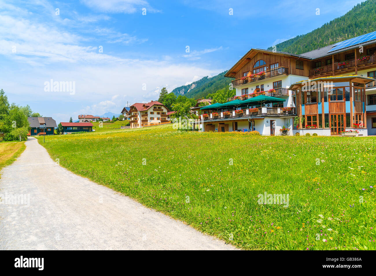 Path in alpine village with traditional countryside houses on shore of Weissensee lake in summer landscape of Alps Mountains, Au Stock Photo