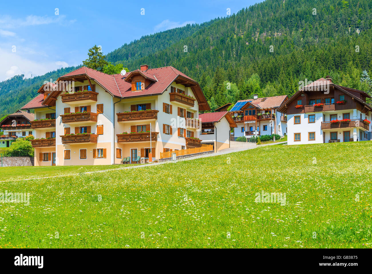 Traditional countryside houses in alpine village on shore of Weissensee lake in summer landscape of Alps Mountains, Austria Stock Photo